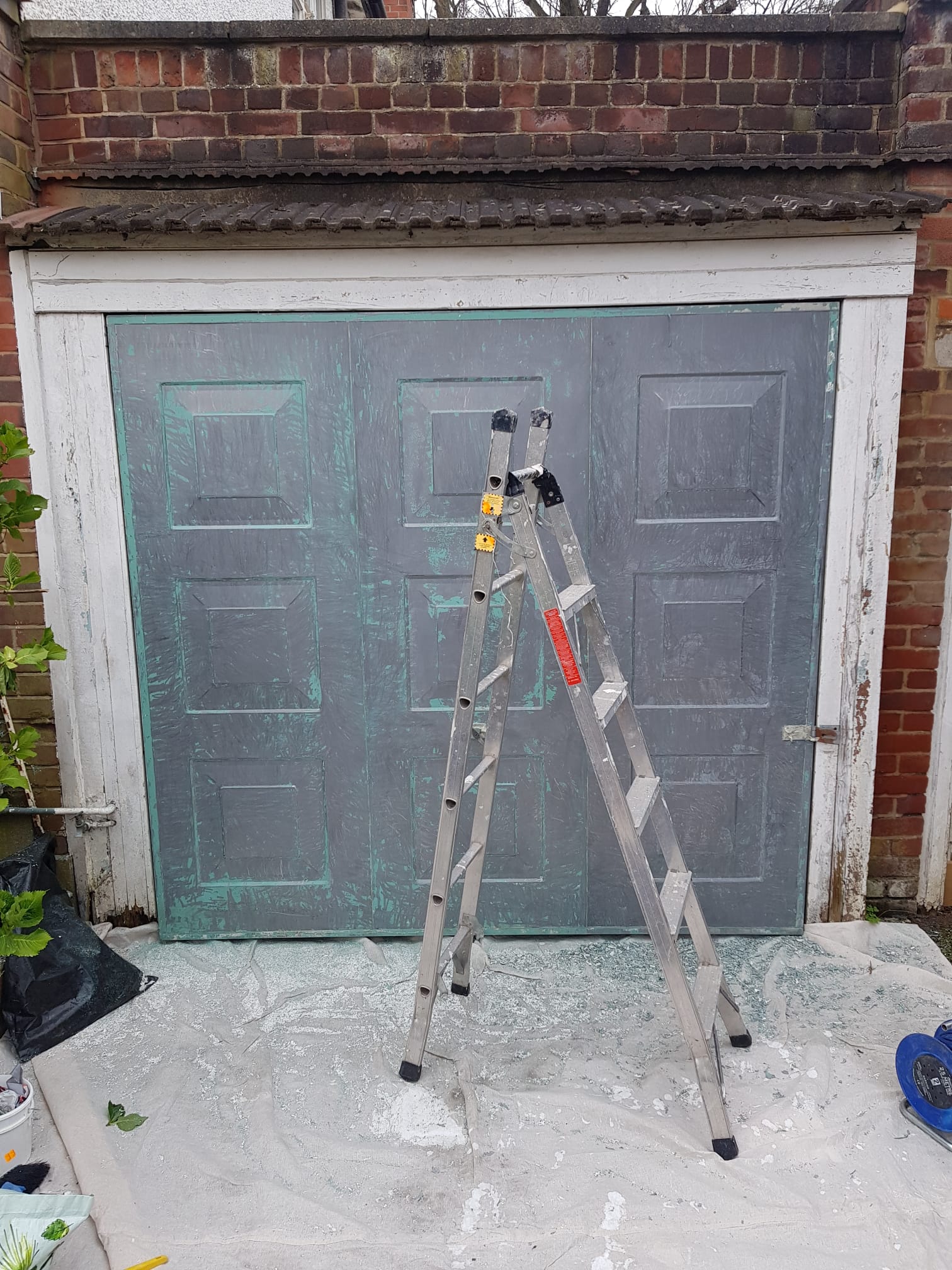 Garage door before repainting, showing worn and faded paintwork.