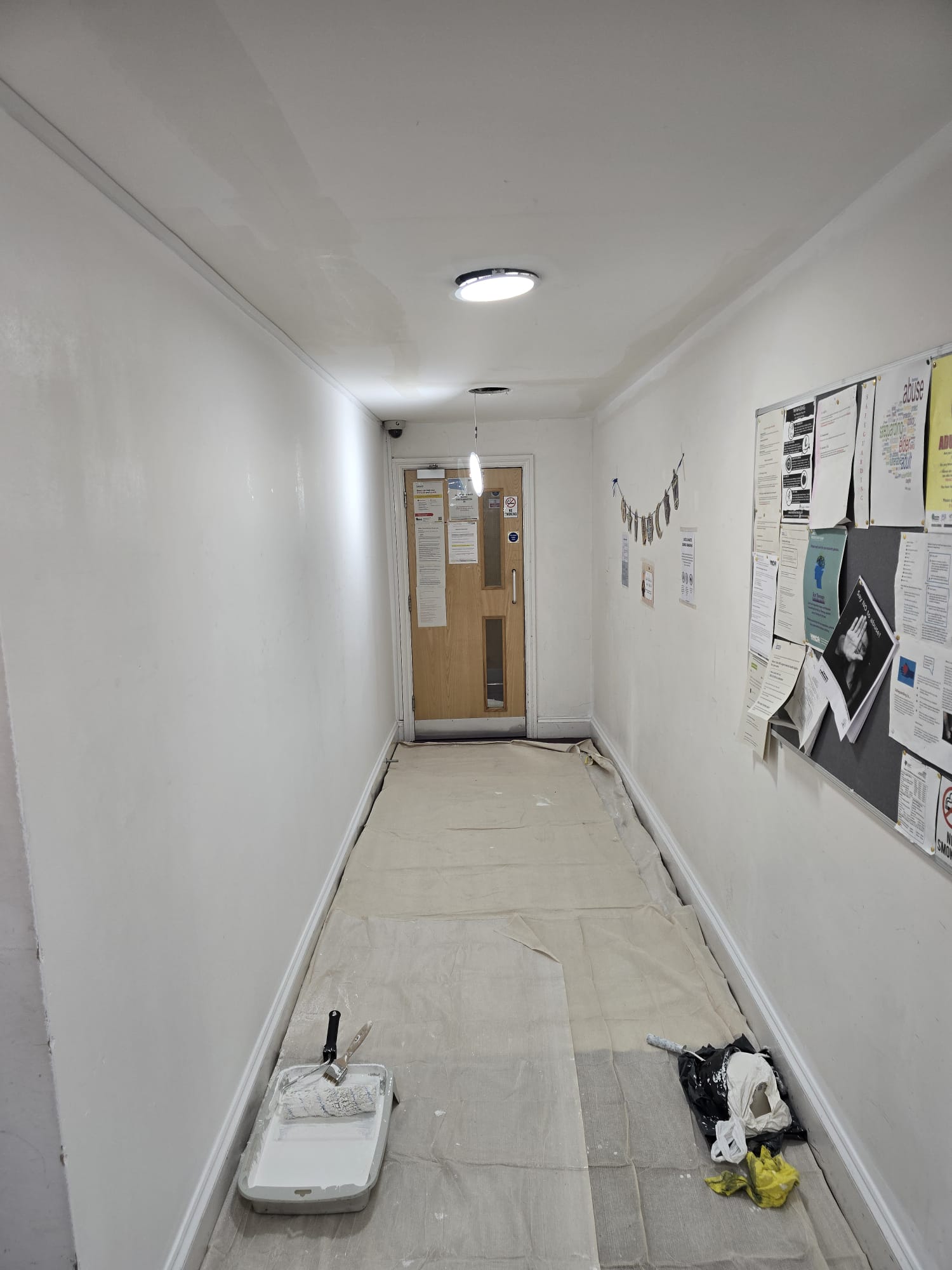 Communal hallway after repainting, finished in fresh white and grey.