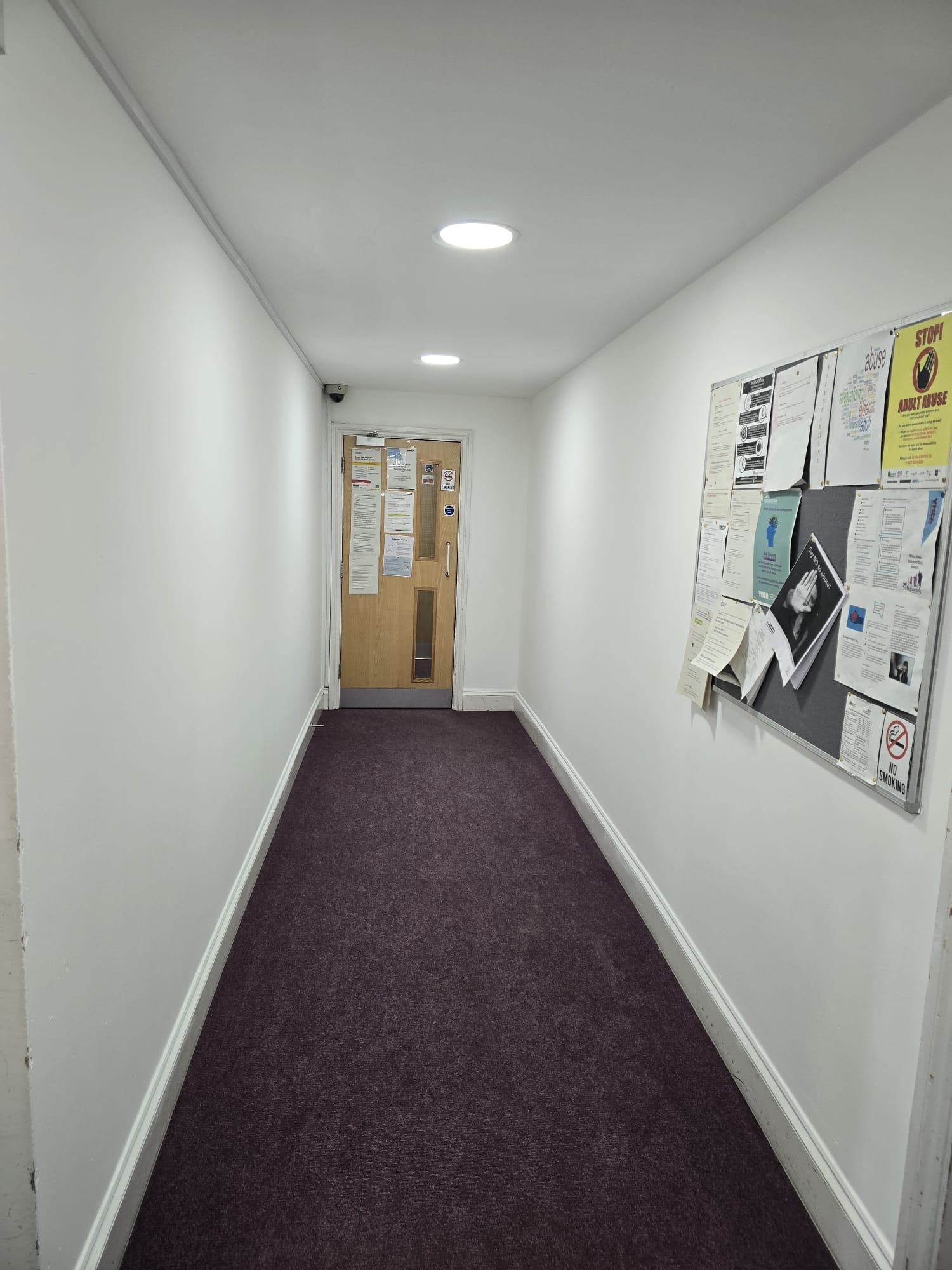 Communal hallway before repainting, showing scuffed and dated walls.