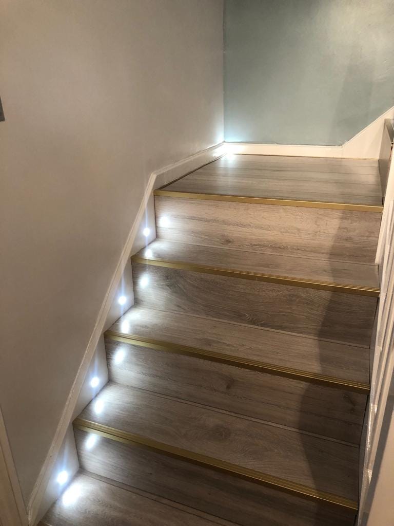 Staircase fitted with new wood-effect treads, brass edging strips and LED step lights.