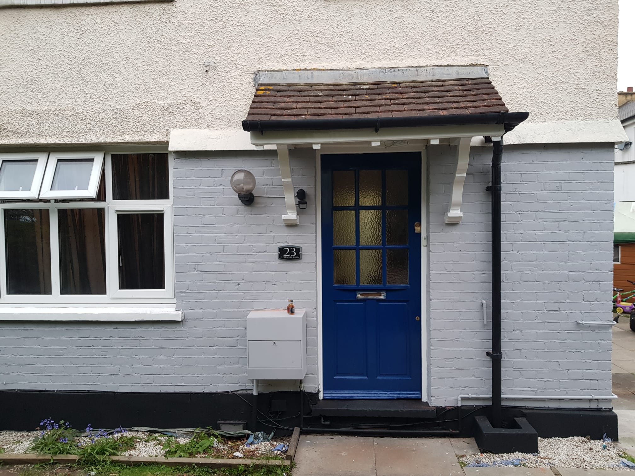 Painted grey brickwork and blue front door on a home in London.