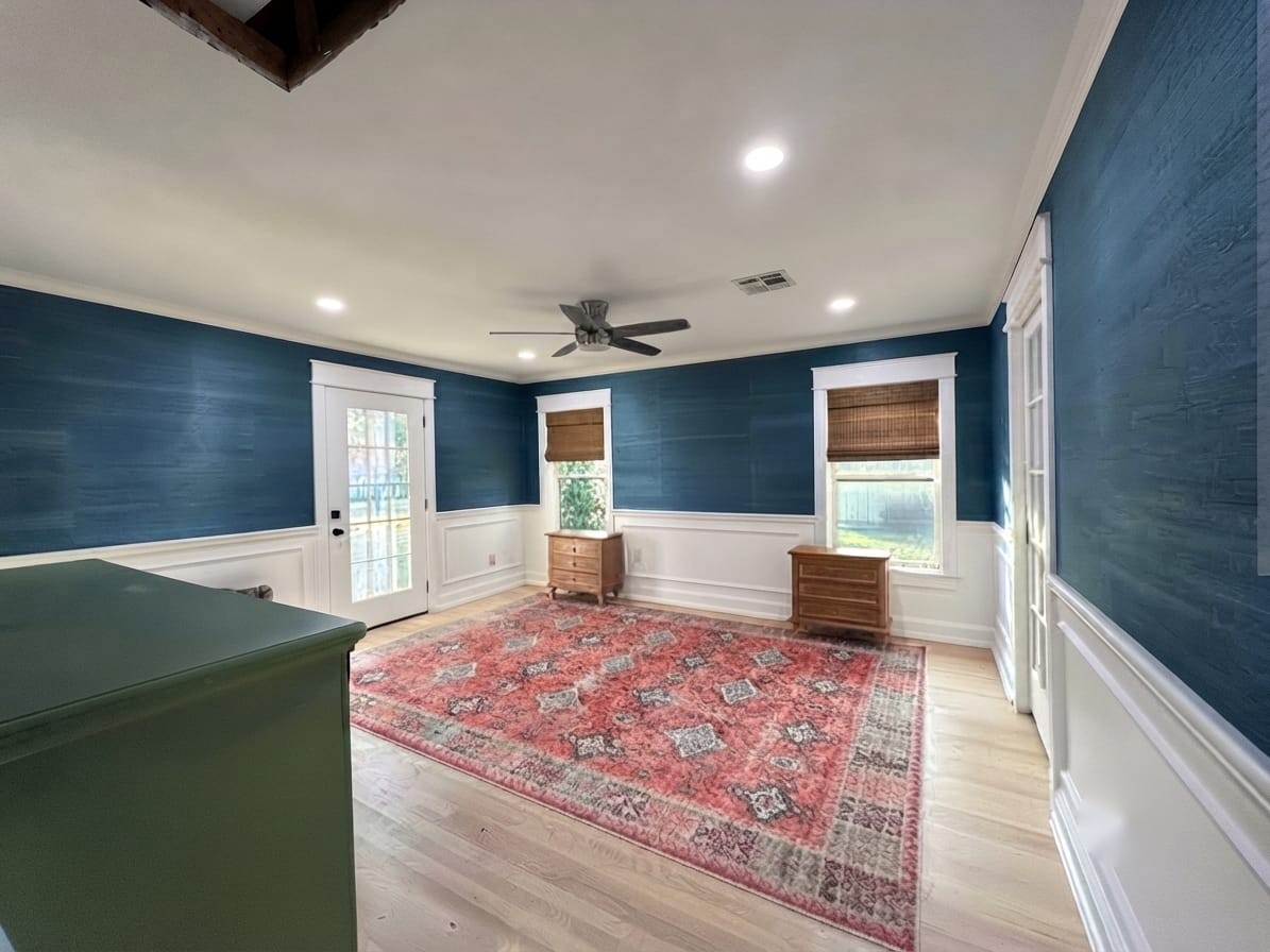 Freshly decorated room with a textured blue feature wall, white wainscoting and wood flooring.