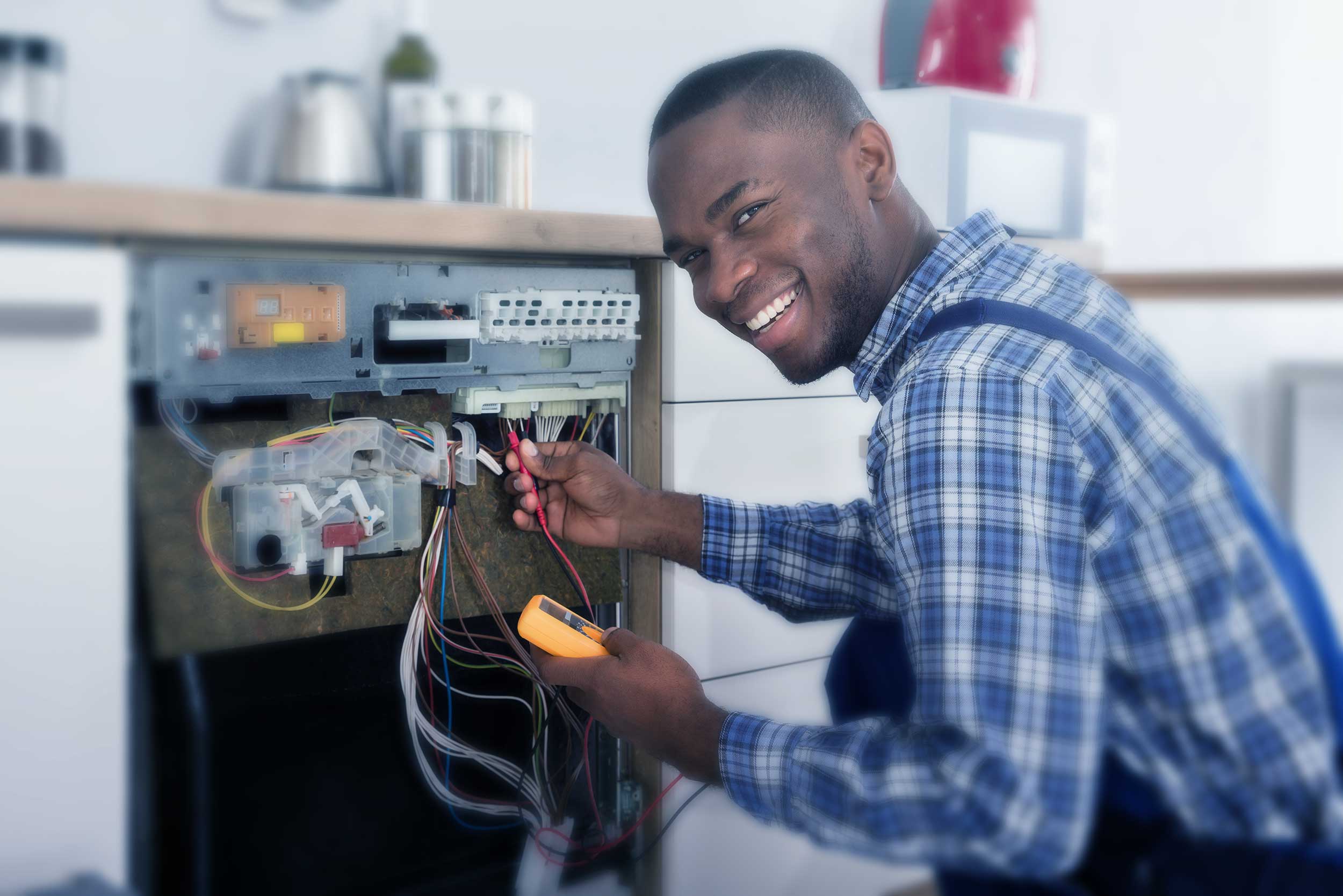 Technician using a multimeter to test wiring on an open appliance control panel as part of a home maintenance job.