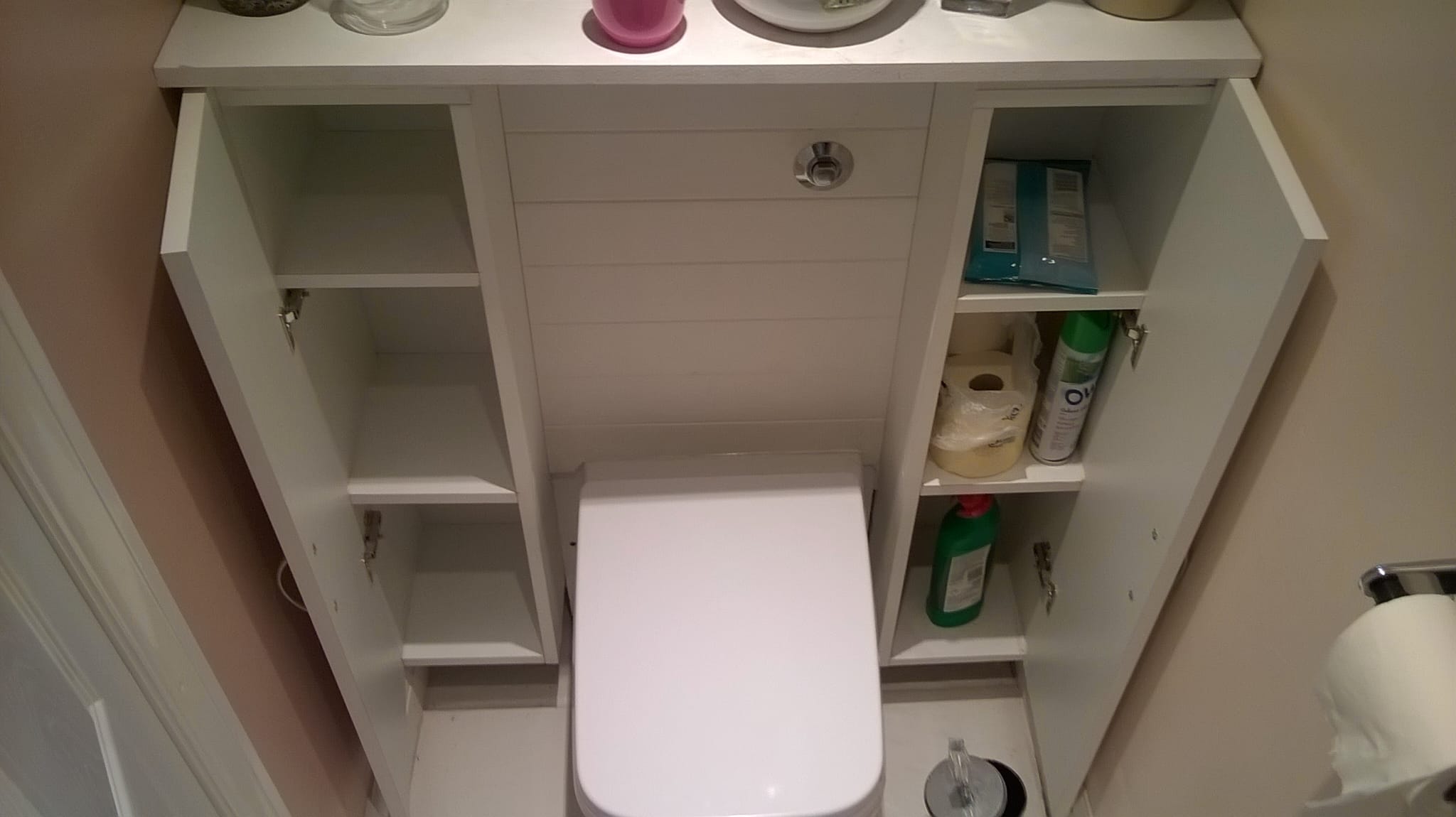 Built-in bathroom storage cabinet around a toilet.